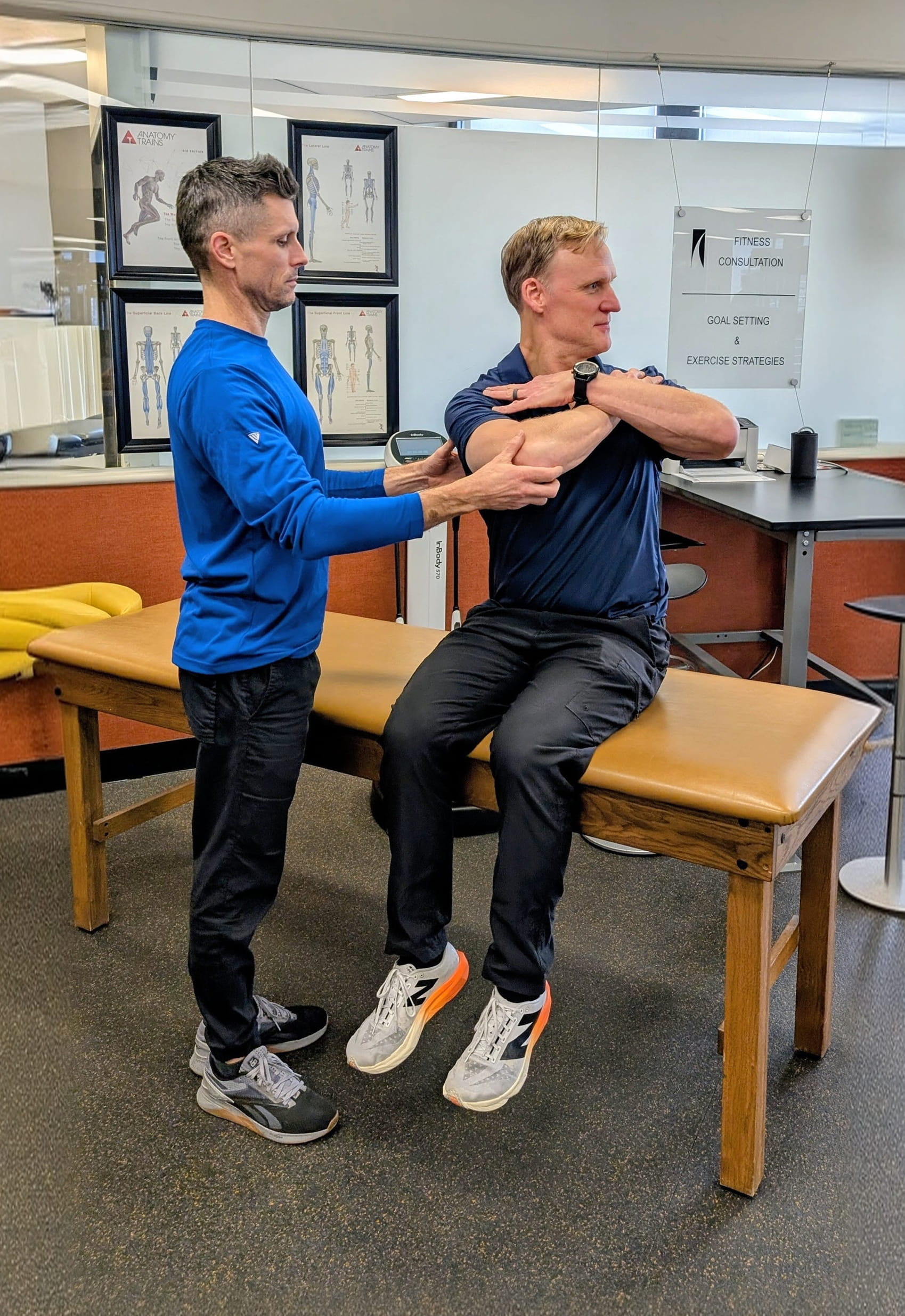 Adelaide Club TPI-certified trainer assessing a golfer's shoulder mobility on a treatment table, illustrating the personalized golf fitness assessment process for off-season swing improvement
